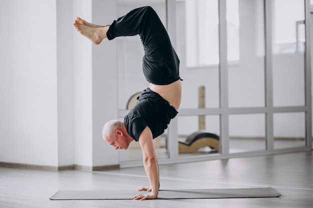 Übendes Yoga des Mannes in der Turnhalle