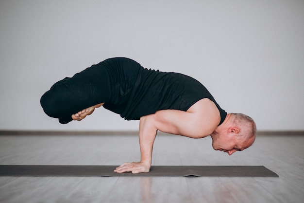 Übendes Yoga des Mannes in der Turnhalle