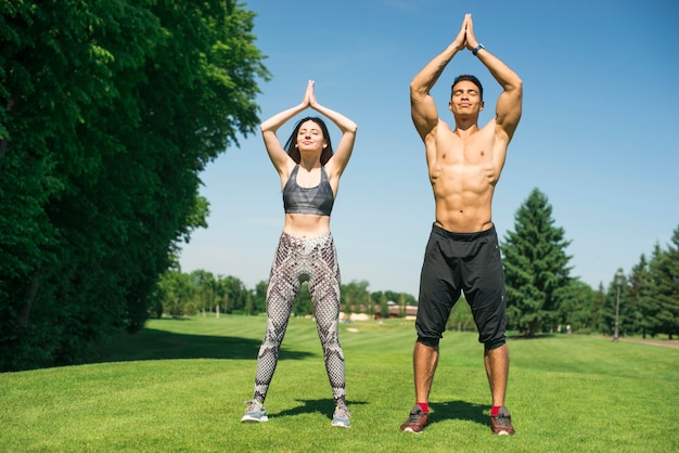 Übendes Yoga des Mannes und der Frau im Freien