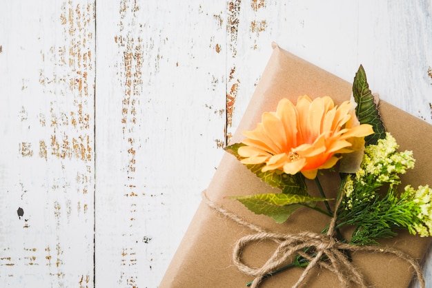 Über der braunen Geschenkbox verziert mit Blumen auf hölzernem strukturiertem Hintergrund