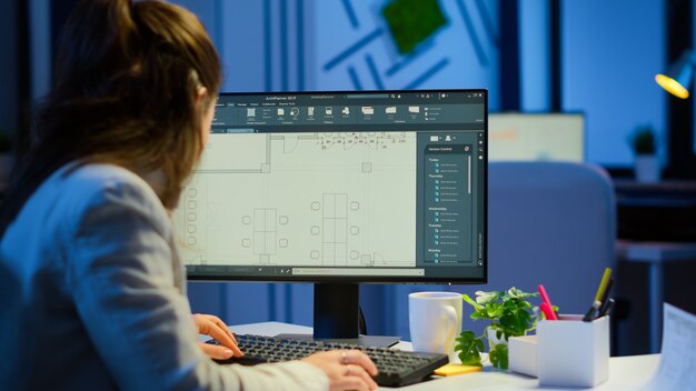 Über die Schulter geschossener Ingenieur, der mit Architekturplänen arbeitet, CAD-Software auf Desktop-Computer. Designer, der Architekturpläne von Gebäuden verwendet, die Überstunden machen, erstellen und studieren