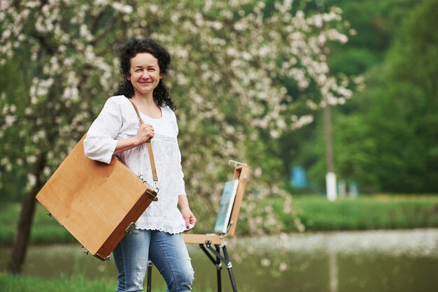 Bereit für eine Arbeit. Reife Maler mit Instrumentenkoffer machen einen Spaziergang im schönen Frühlingspark