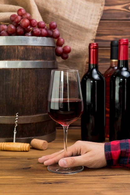 Übergeben Sie das Halten des Glases Weins mit Flaschen und Barre