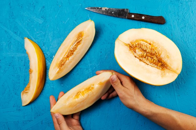 Übergeben Sie das Halten einer Wassermelonenscheibe auf blauem Hintergrund