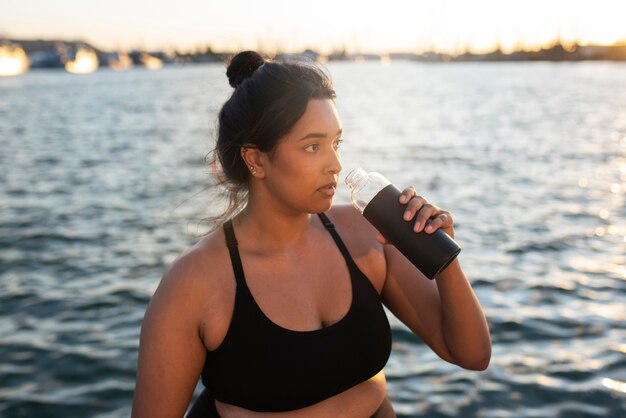 Übergewichtige Frau, die nach dem Training im Freien mit Wasser hydratisiert wird