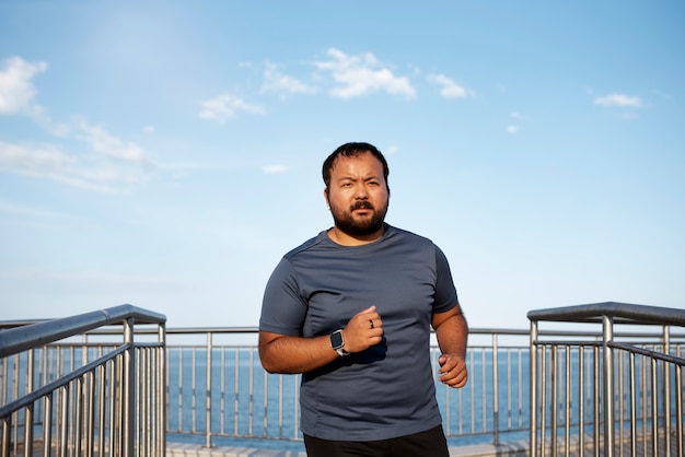 Übergewichtiger Mann, der draußen am See joggt