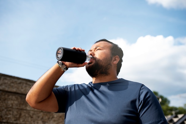 Übergewichtiger Mann, der nach dem Training mit Wasser hydratisiert