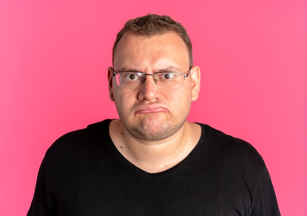 Übergewichtiger Mann in Brille mit schwarzem T-Shirt-Lookign an der Kamera missfiel über Pink