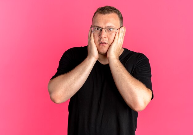 Übergewichtiger Mann in Brille mit schwarzem T-Shirt überrascht und erstaunt über Pink