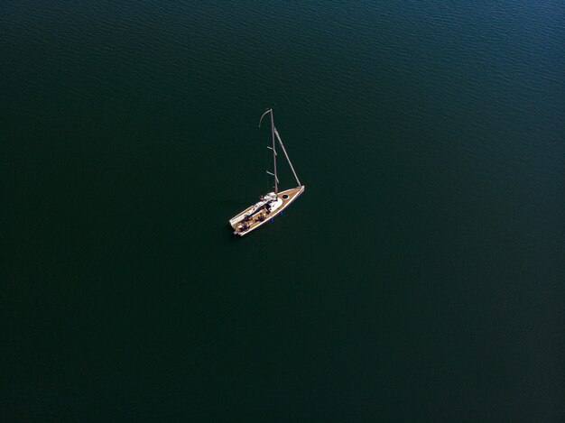 Überkopf-Drohnenfotografie eines Segelboots in einem schönen See an einem sonnigen Tag