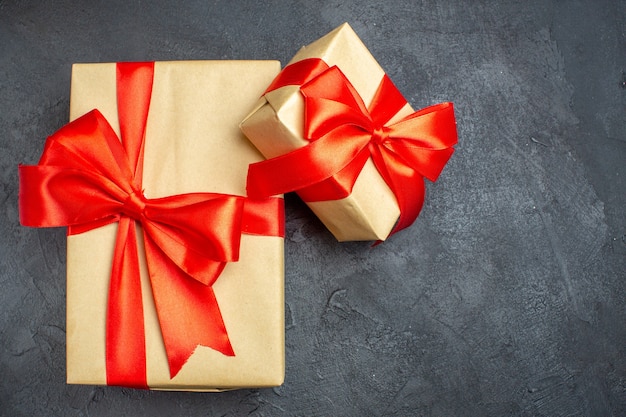 Überkopfansicht des Weihnachtshintergrundes mit schönen Geschenken mit bogenförmigem Band auf der rechten Seite auf einem dunklen Hintergrund