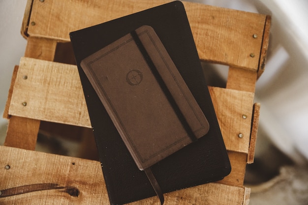 Überkopfaufnahme eines Notizbuchs auf der Bibel auf einer Holzkiste