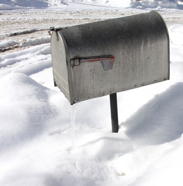 Überkopfaufnahme eines silbernen Briefkastens mit Schnee in der Oberfläche während des Winters