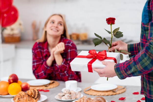 Überraschende Frau des Nahaufnahmemannes mit Rose und Geschenk