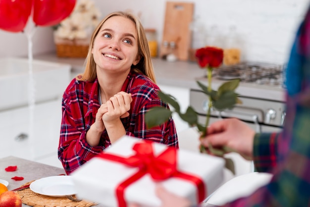 Überraschende Frau des Nahaufnahmemannes mit Rose und Geschenk