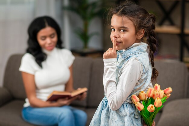 Überraschende Mutter des kleinen Mädchens mit Blumen