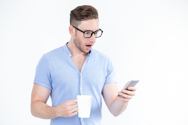 Überrascht junger Mann in Gläser mit Smartphone