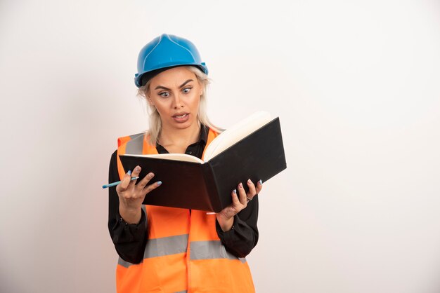 Überraschte Arbeiterin, die Notizen auf weißem Hintergrund liest. Hochwertiges Foto