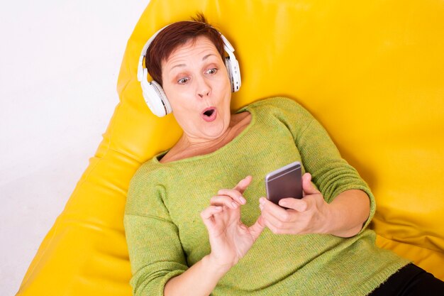 Überraschte Frau auf hörender Musik der Couch