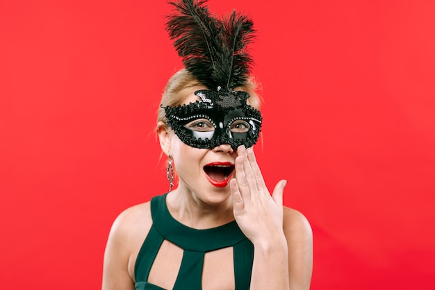 Überraschte Frau in der schwarzen Karnevalsmaske