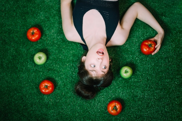 Überraschte Frau inmitten von Äpfeln und Tomaten