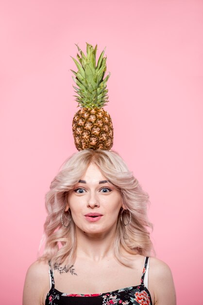 Überraschte Frau mit Ananas auf Kopf