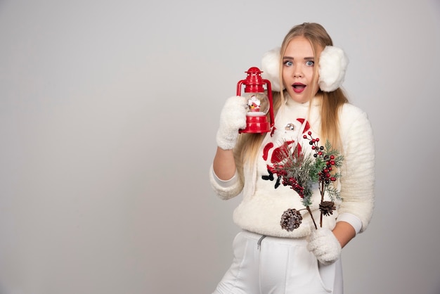 Überraschte Frau mit Stechpalmenbeeren und Weihnachtslampe.