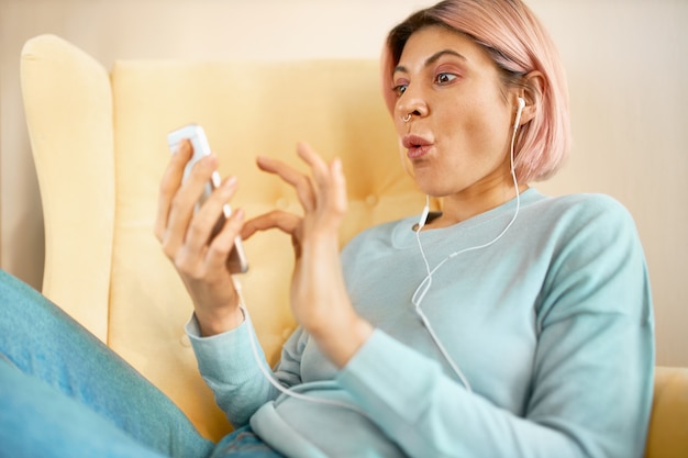 Überraschte junge Frau, die Newsfeed über Social-Media-Konto scrollt, schockierten Blick.