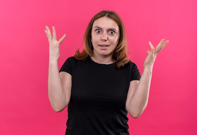 Überraschte junge lässige Frau mit erhobenen Händen auf isolierter rosa Wand