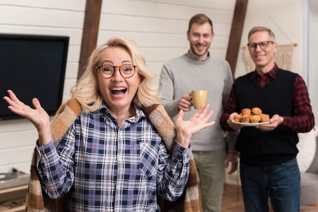 Überraschte Mutter mit dem Sohn und Vater, die Muffins halten