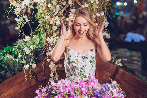 Überraschte schöne junge Frau, die bunten Blumenblumenstrauß im Garten betrachtet