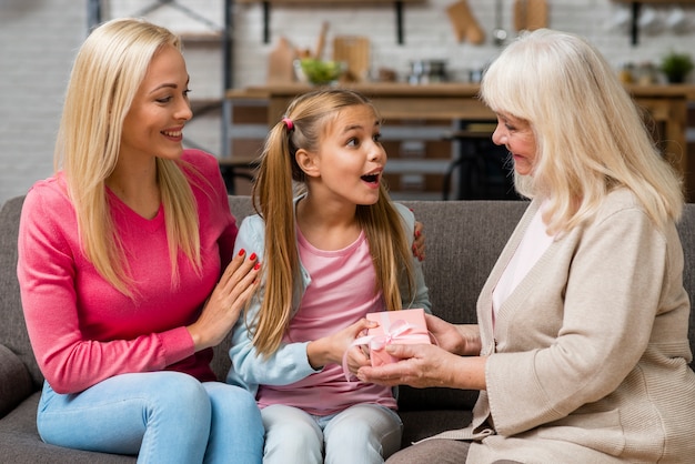 Überraschte Tochter, die ein Geschenk von ihrer Großmutter empfängt