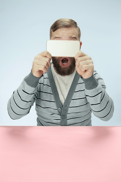 Überraschter Geschäftsmann, der am Telefon am Tisch sitzt