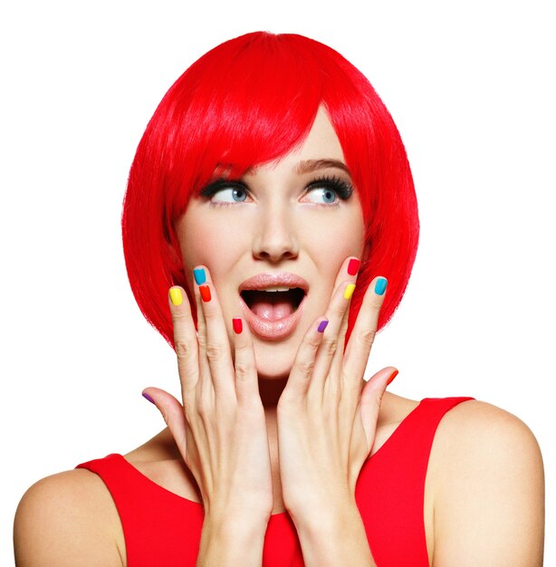 Überraschtes Gesicht einer jungen hübschen Frau mit leuchtend roten Haaren und mehrfarbigen Nägeln.