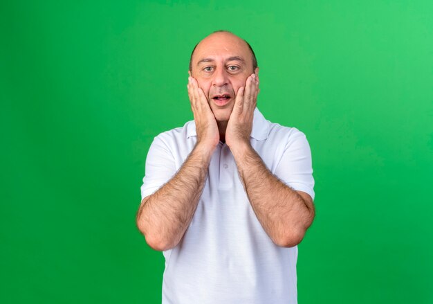 Überraschtes lässiges reifes Mann bedeckt Gesicht mit den Händen lokalisiert auf grüner Wand