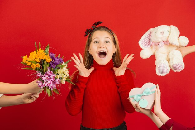 Überraschtes und erstauntes kleines Mädchen, das viele Geschenke zum Valentinstag erhält