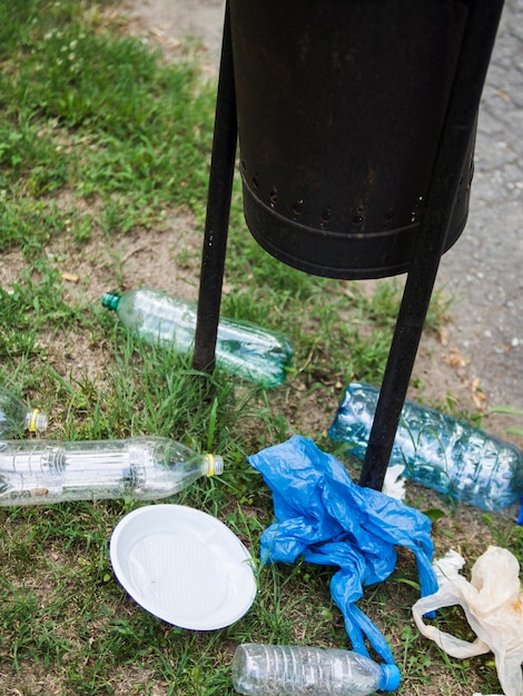 Überschüssiger Plastikmüll unter dem schwarzen Behälter am Park