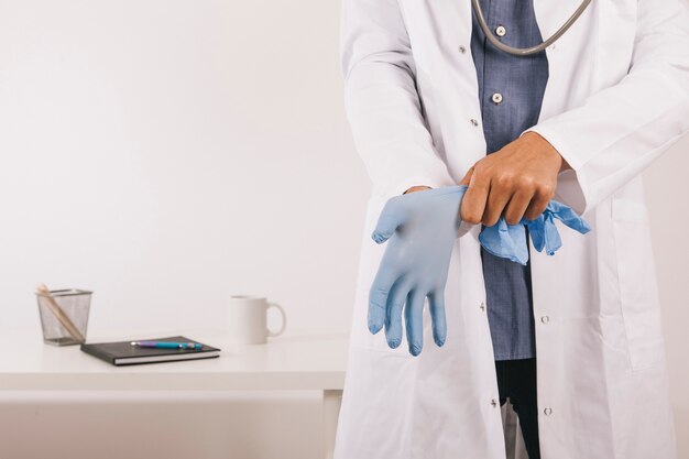 Berufsarzt trägt Handschuhe in seinem Büro