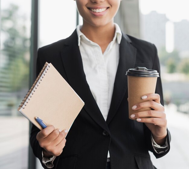 Berufsfrau, die Notizblock und Kaffee hält