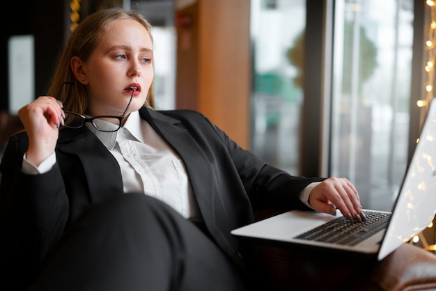 Berufstätige Frau im stilvollen Anzug im Büro mit Laptop