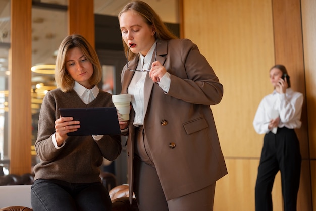 Kostenloses Foto berufstätige frauen in stylischem anzug im büro mit tablet-gerät