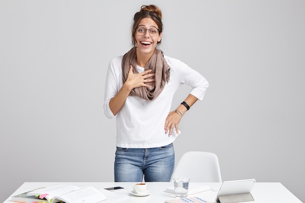 Berufung und Kreativität. Fröhliche junge erfolgreiche talentierte Designerin, die Schal und Brille stehend trägt