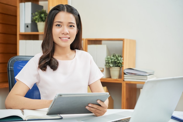 Überzeugte moderne Frau mit Tablette im Büro