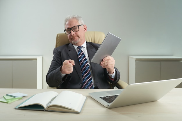 Überzeugter Büroangestellter, der auf Kamera zeigt