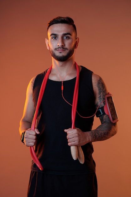 Überzeugter Sportler mit Kopfhörern und springendem Seil