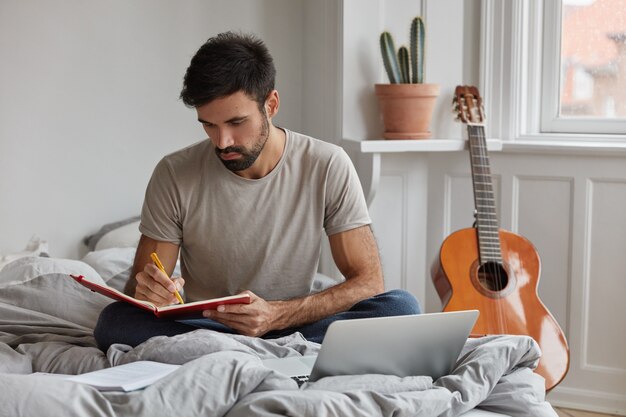 beschäftigt bärtigen Kerl posiert zu Hause während der Arbeit