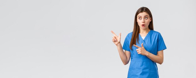 Beschäftigte im Gesundheitswesen verhindern Virusversicherung und Medizinkonzept Überrascht weibliche Krankenschwester oder Ärztin in blauen Scrubs, die mit den Fingern in der oberen linken Ecke nach Luft schnappen