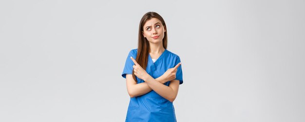 Beschäftigte im Gesundheitswesen verhindern Virusversicherung und Medizinkonzept Krankenschwester vor komplizierter Wahl Arzt in blauen Scrubs, die seitwärts zeigen und eine schwierige Entscheidung treffen, die unentschlossen ist