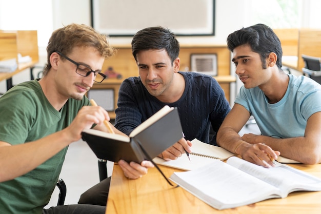 Beschäftigte nachdenkliche multiethnische Studenten, die für Prüfung sich vorbereiten