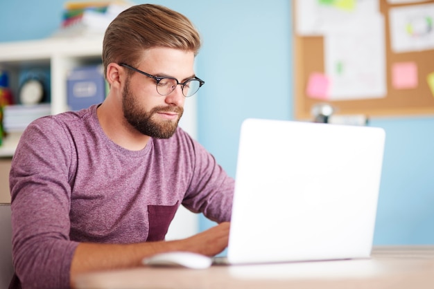 Beschäftigter Mann, der an weißem Laptop arbeitet